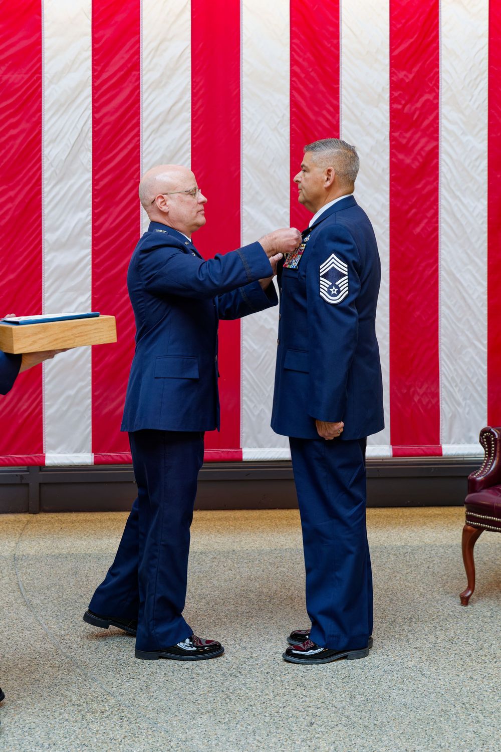 Senior Air Force officer pins a medal on a Chief Master Sergeant at a retirement ceremony.