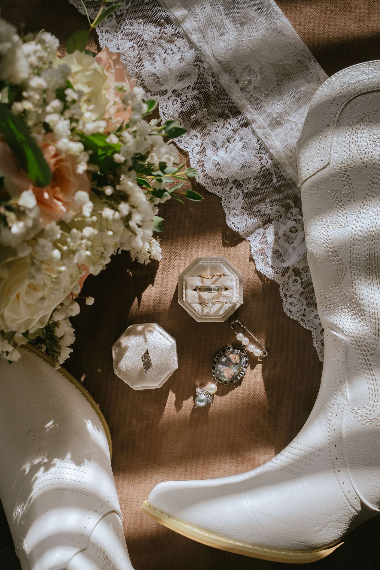 Melissa's white boots, wedding rings in their boxes, bouquet and lace veil arranged together before the ceremony.