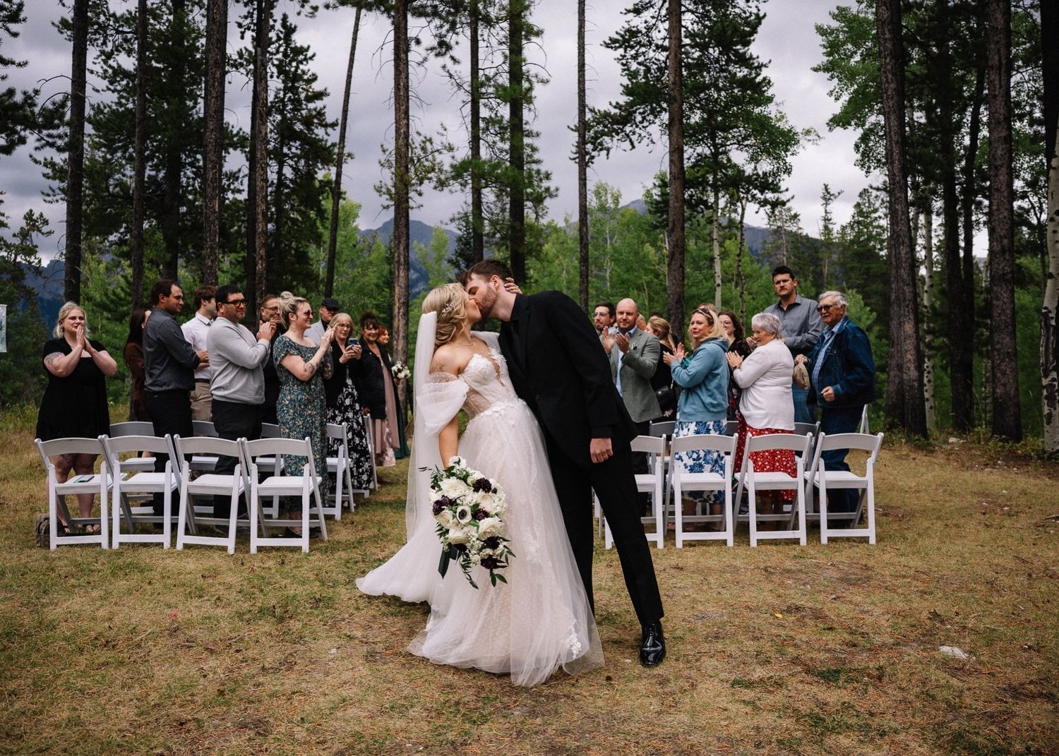 Guests applaud as the couple kiss after their Tree Island ceremony at the Canmore Nordic Centre in Canmore
