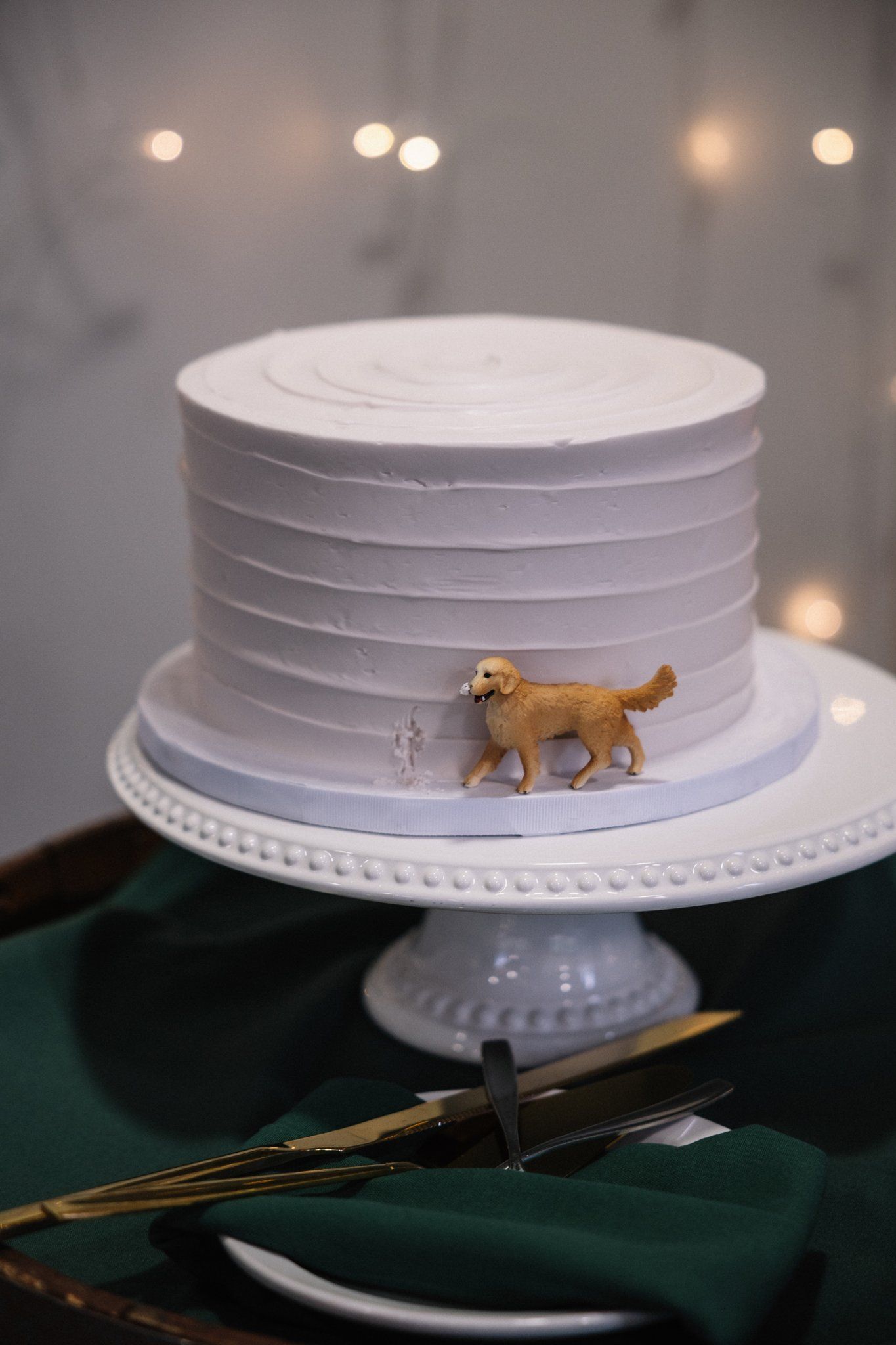 White wedding cake by KAKE by Darci with a golden retriever topper of the couple's dog Ara, Canmore wedding
