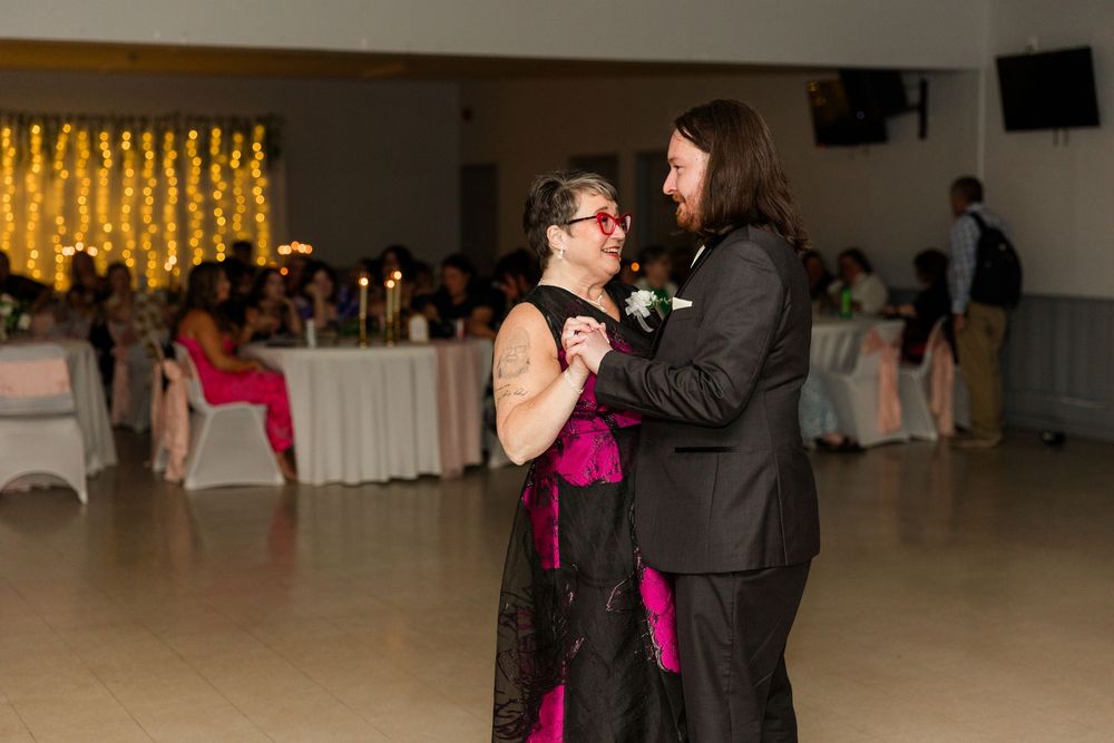 Couple shares a romantic first dance at a wedding reception with warm string lights glowing in the background.