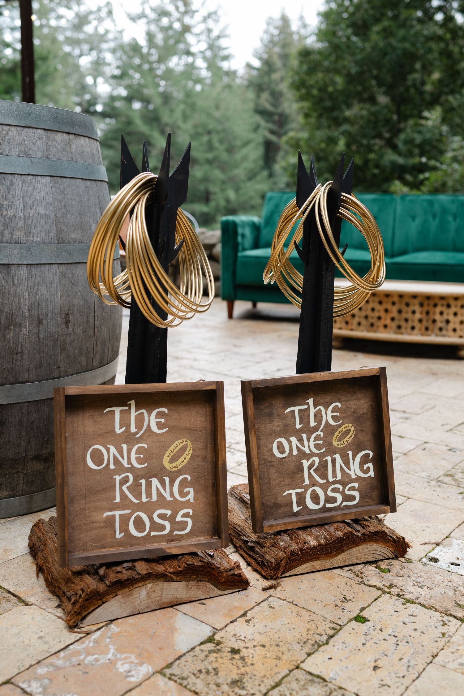Lord of the Rings themed wedding ring toss game with gold rings on black stands and rustic wooden signs outdoors.