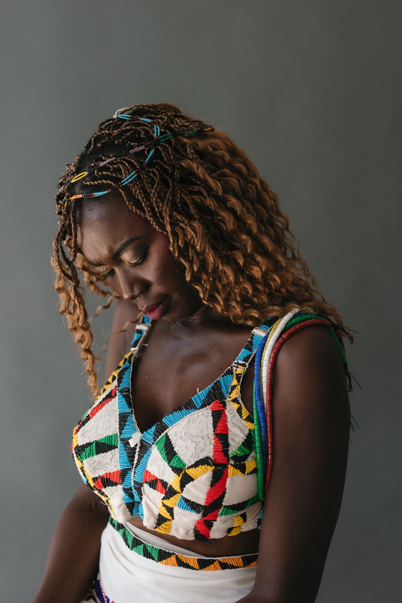 Woman with braided hair adorned with colorful clips wearing African print crop top.