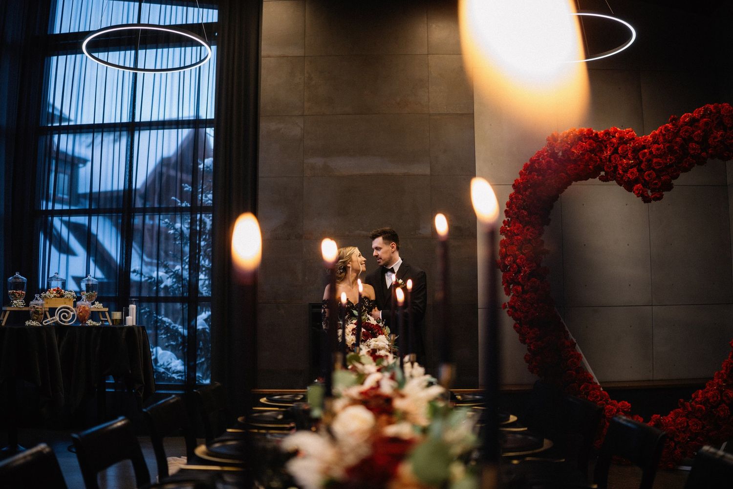 Bride and groom framed by glowing candles and a red rose heart at their Mainspace reception