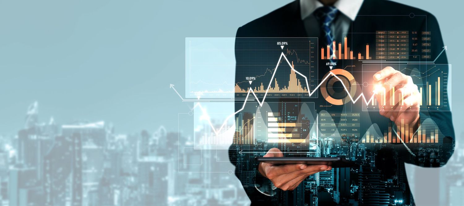 Businessman analyzing digital financial charts and graphs on a virtual holographic display over a city skyline.