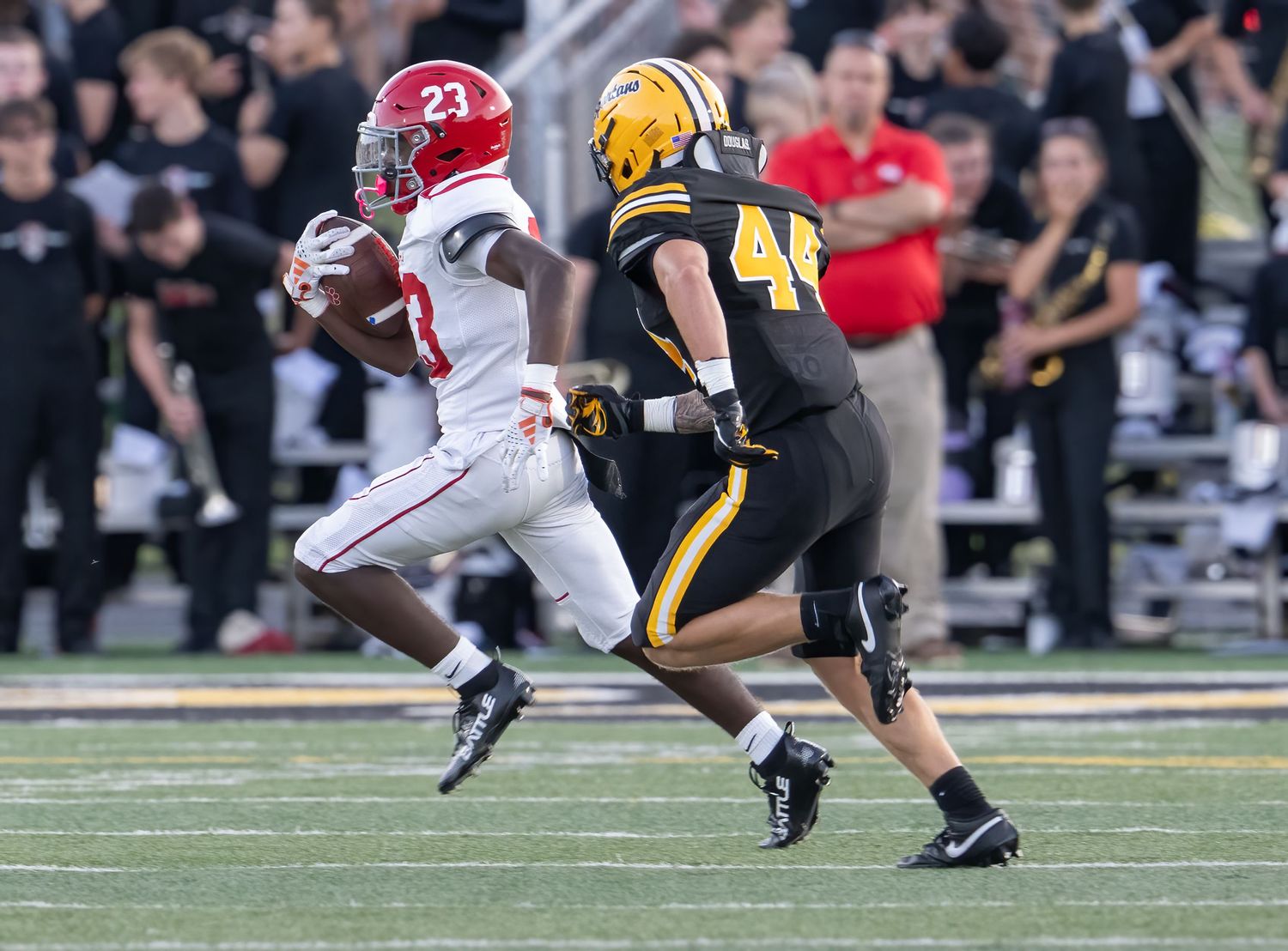 Alabama football player #23 in white uniform runs past defender #44 in black during a college football game.