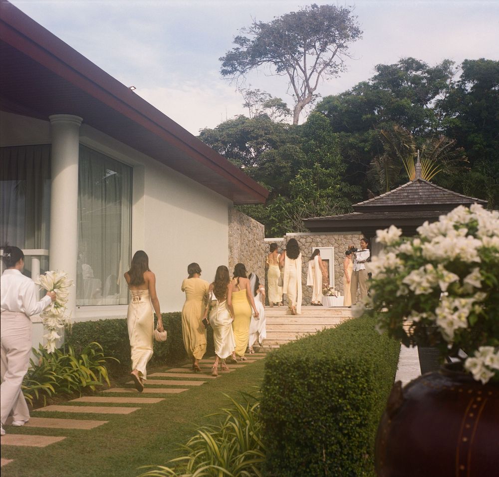 Garden pathway with white statues and tropical landscaping leading to a resort building.