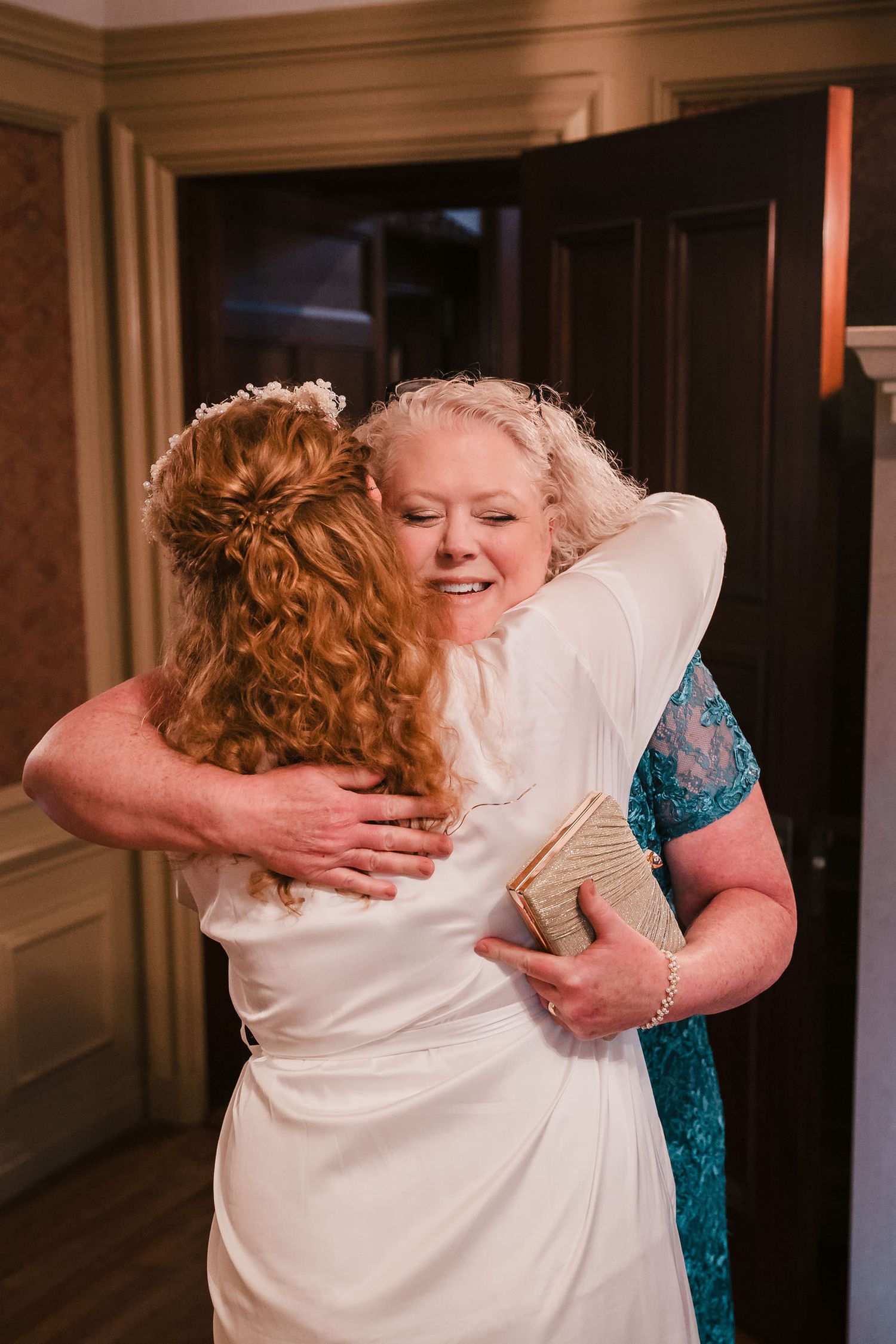 Bride and her mother embracing in tears after the reveal of a wedding dress made from the mother's gown.