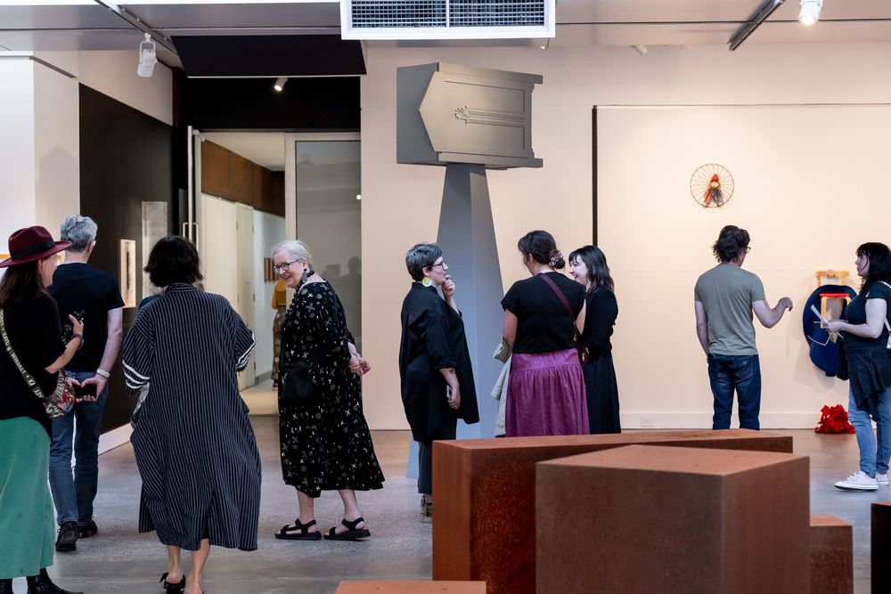 Visitors explore a contemporary art gallery featuring large sculptures and diverse artwork on display.