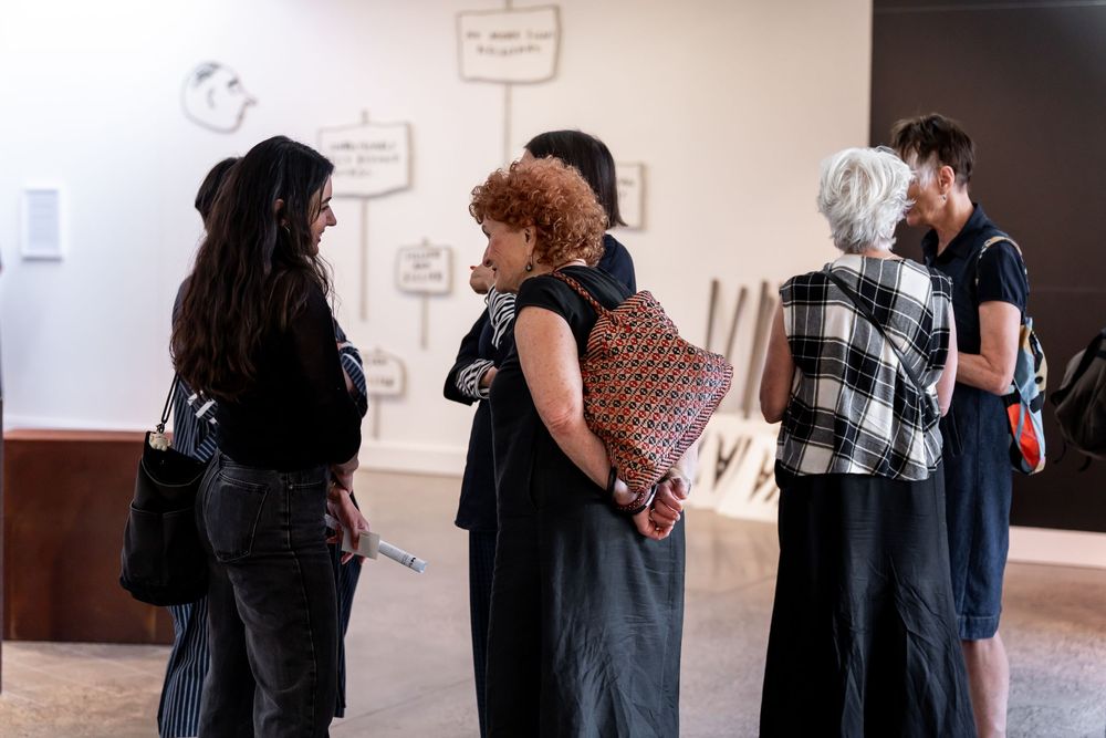 Small group of visitors conversing in a modern art gallery with wall installations.