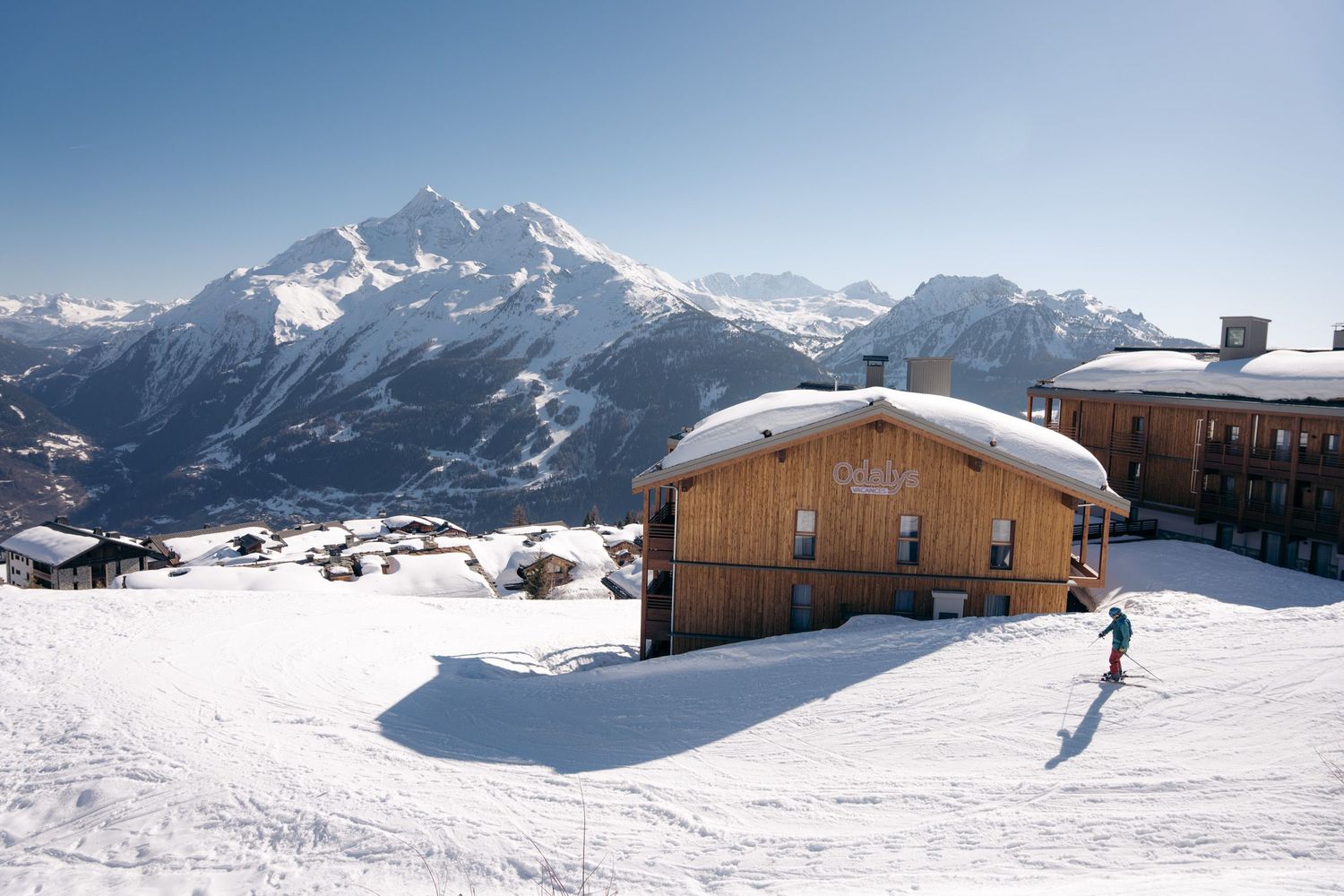 résidence odalys l'ecrin blanc de la rosière avec un skieur dévalant la piste devant