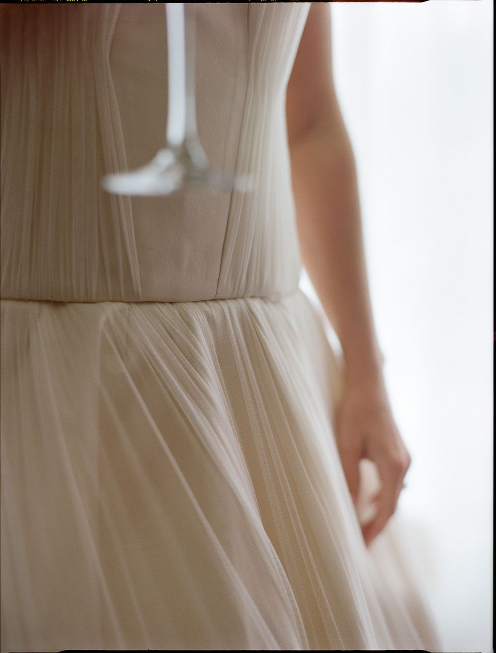 Close-up of a bride in an elegant ivory tulle wedding gown with a fitted bodice and flowing skirt.