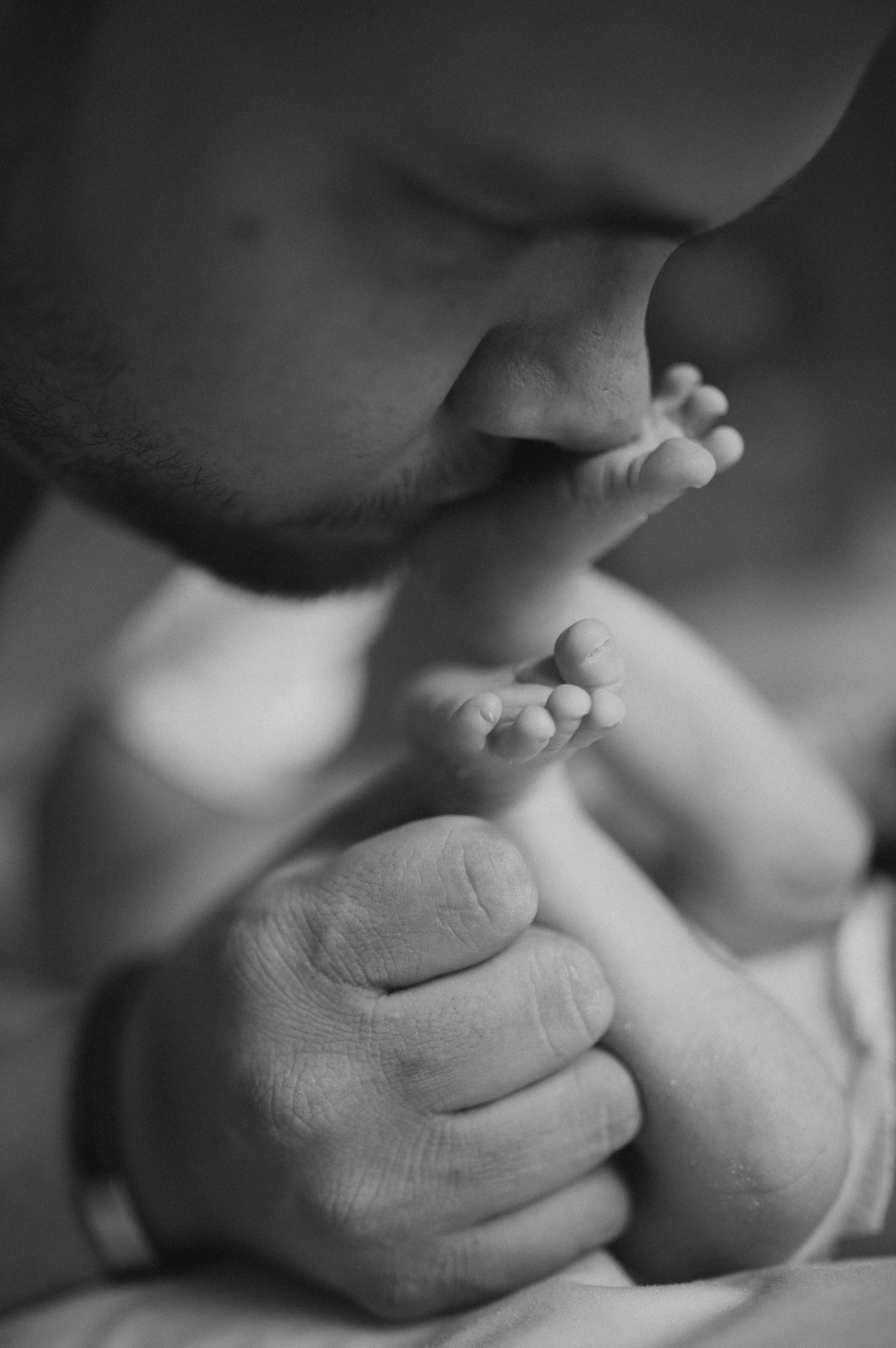 Black and white close-up photograph of tiny baby feet and hands.