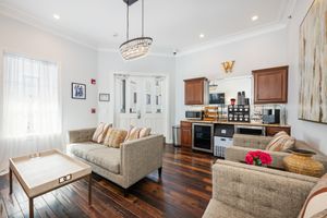 Elegant hotel lobby lounge with hardwood floors, neutral sofas, chandelier, and coffee station.