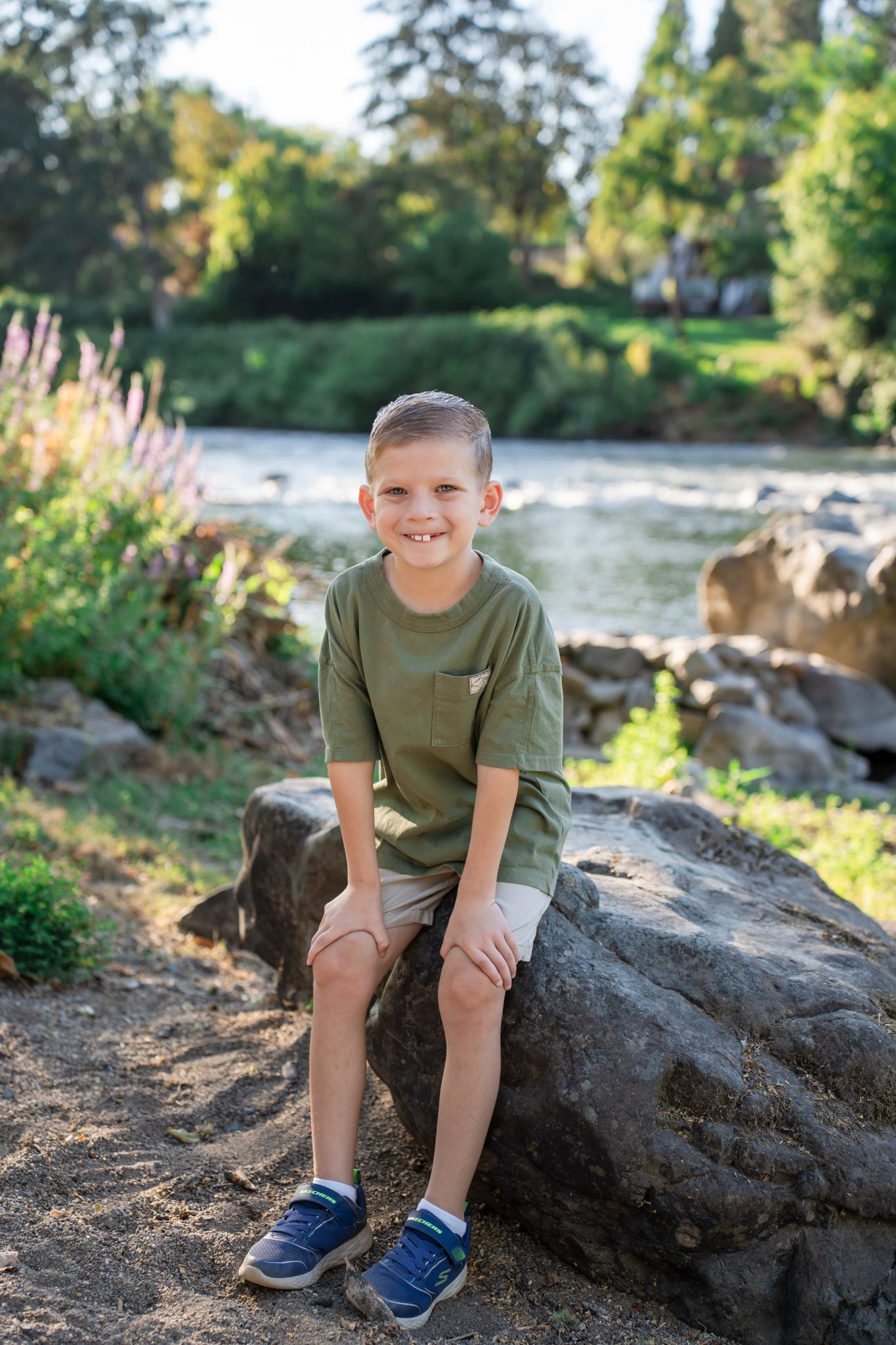 Young boy sitting on the rock with the river behind him