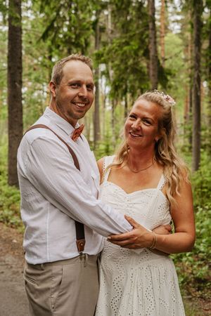 Brudpar står tillsammans i skogen under sin personliga bröllopsfotografering i Ockelbo.