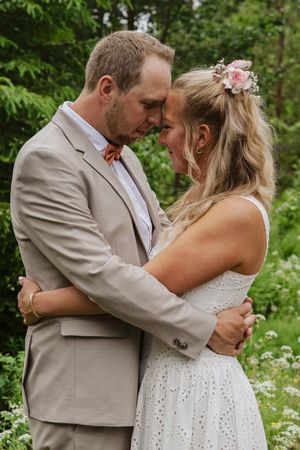 Brudpar står nära varandra i skogen under sin personliga bröllopsfotografering i Ockelbo.