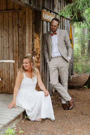 Brudpar poserar tillsammans vid en rustik träbyggnad under sin bröllopsfotografering i Ockelbo.