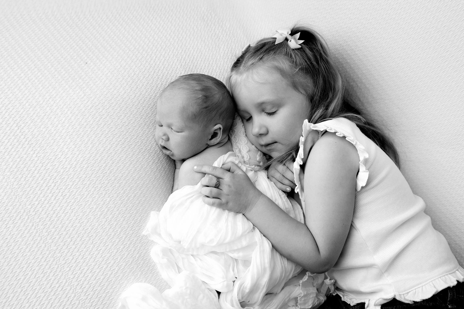 A young girl smiles while kissing a baby's tiny feet, sharing a sweet tender moment.