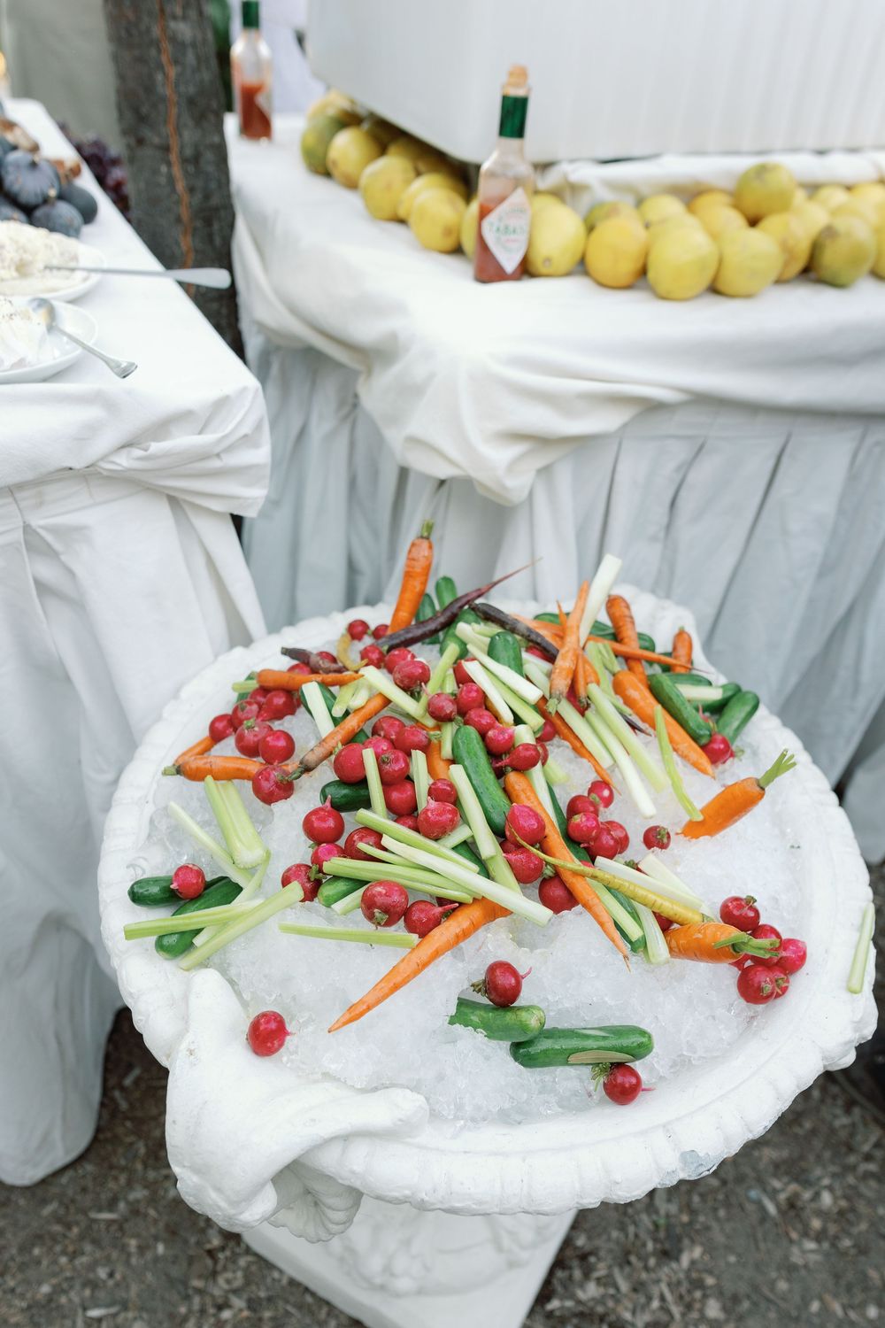 Elegant outdoor wedding crudite display with fresh carrots, celery, cucumbers and cranberries served on ice.