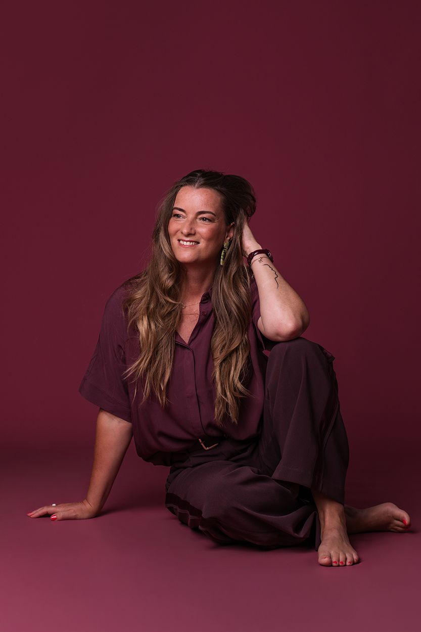 Studio portretshoot voor zakelijke fotografie met een donkerroze achtergrond met vrouwelijke creatieve ondernemer.