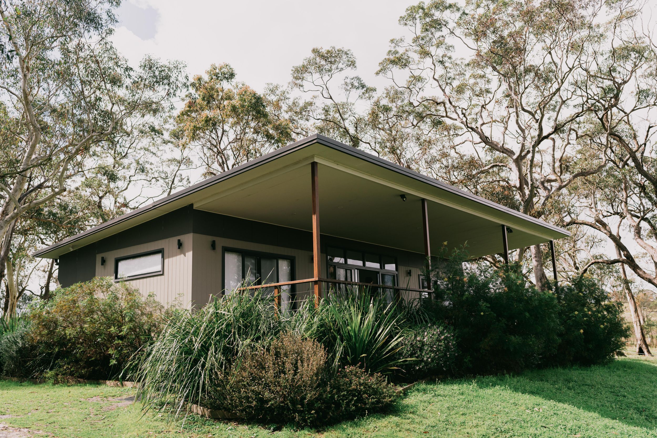 Modern country wedding venue cottage surrounded by native Australian trees and lush garden landscaping.
