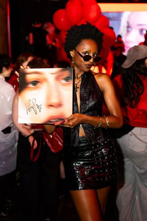 Party attendee poses with signed King Princess album at a New York City queer event.