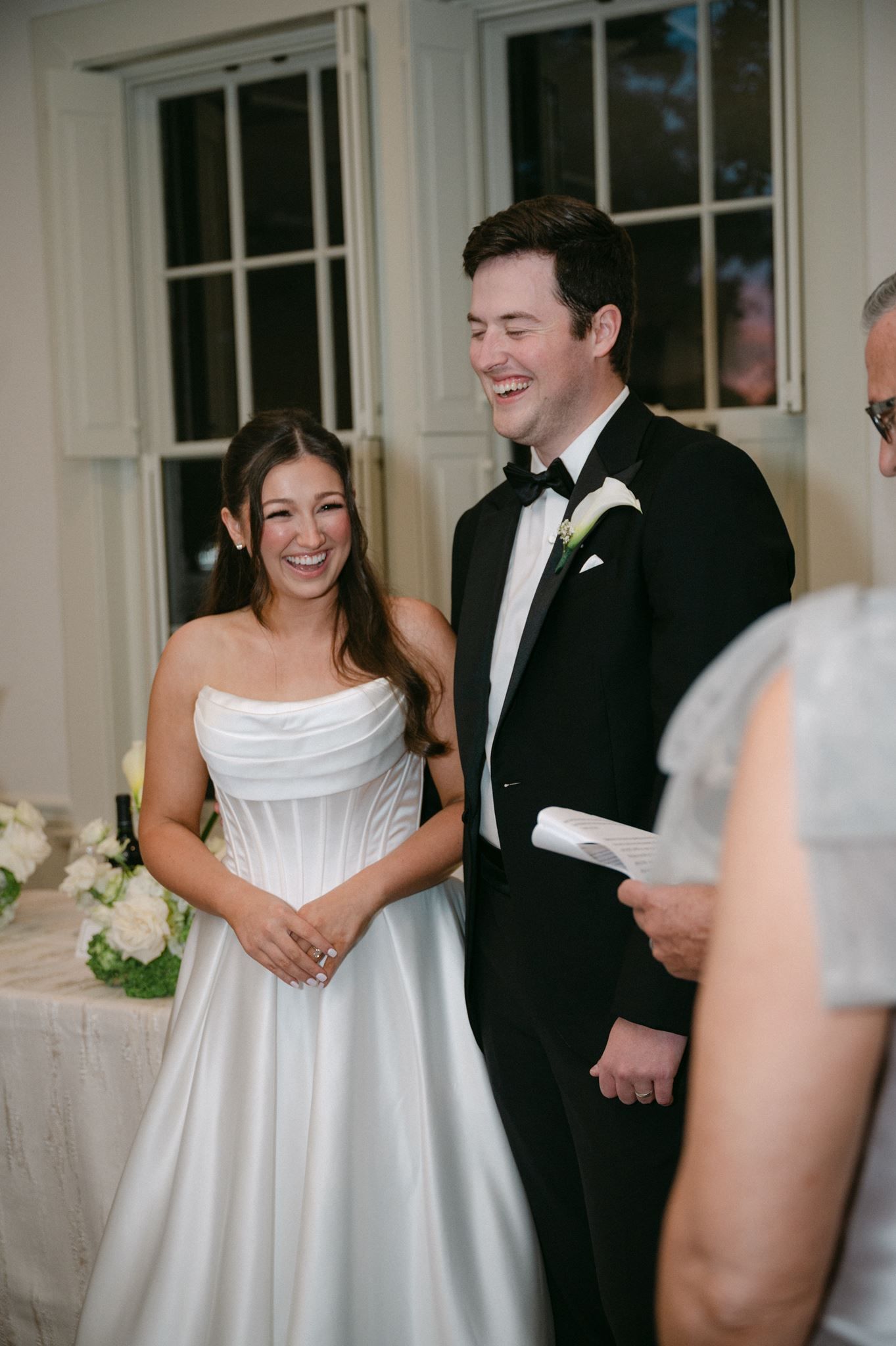 Bride and groom laugh during wedding toasts.