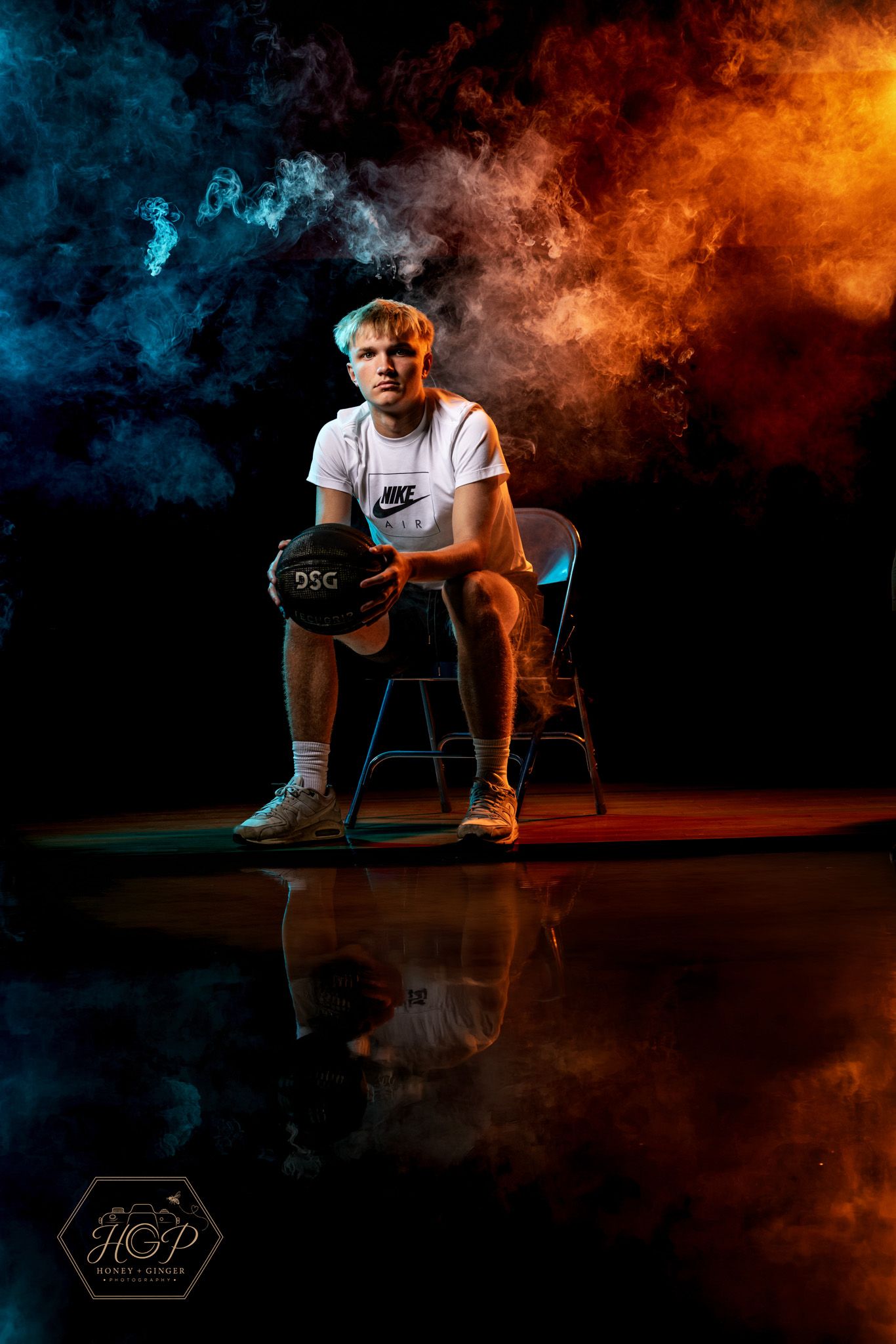 Dramatic senior sports portrait with blue and orange smoke and studio lighting