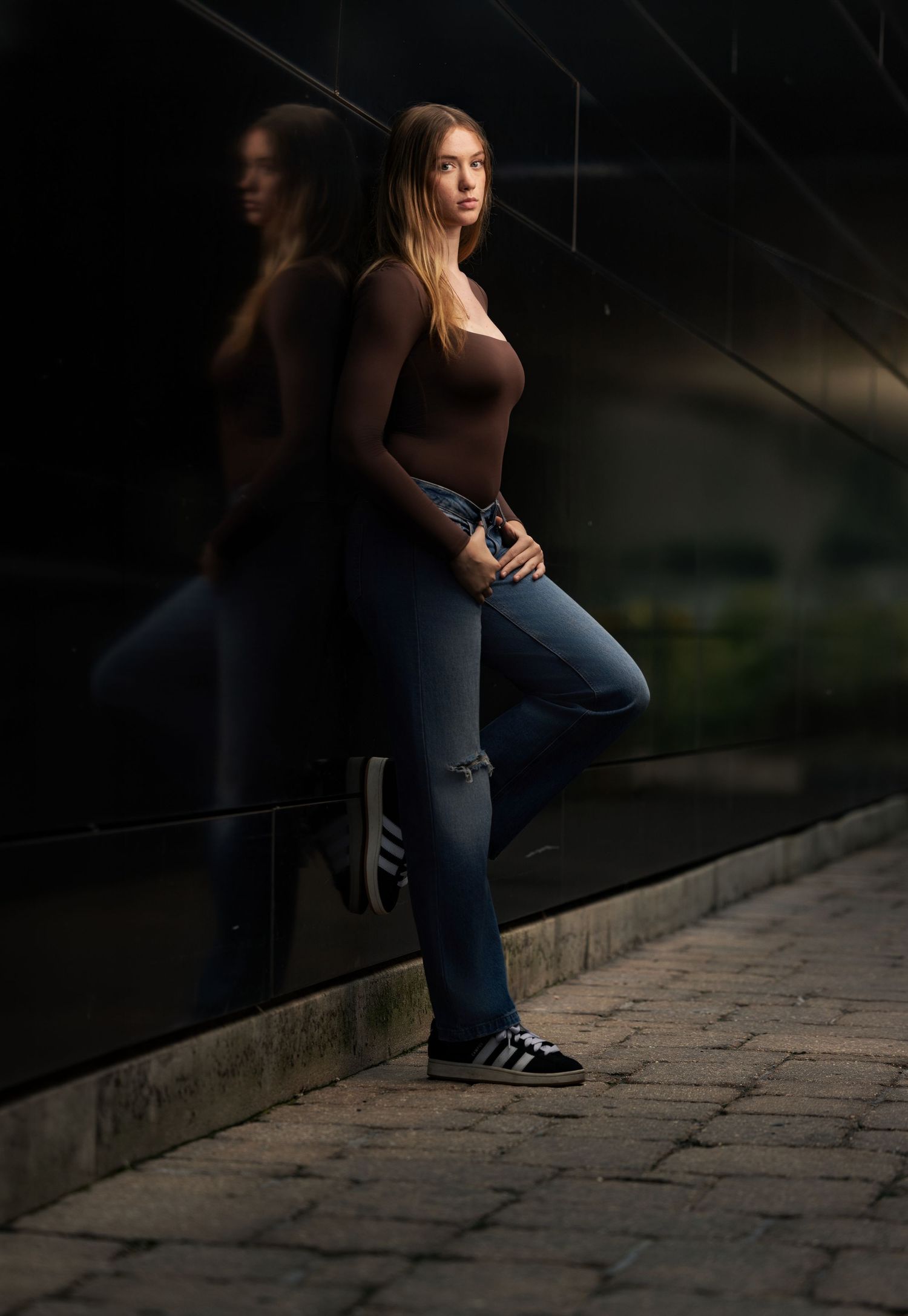 Moody senior portrait of a brunette girl photographed with dramatic outdoor lighting