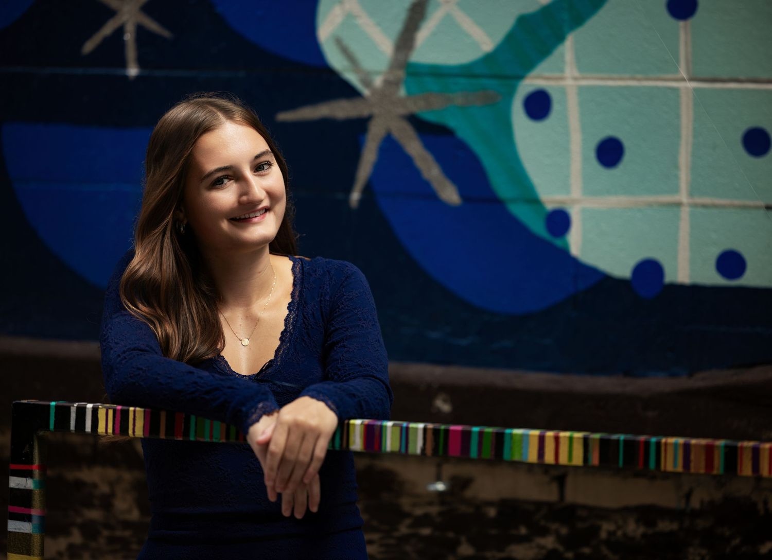 Senior portrait of a brunette girl photographed against a colorful mural