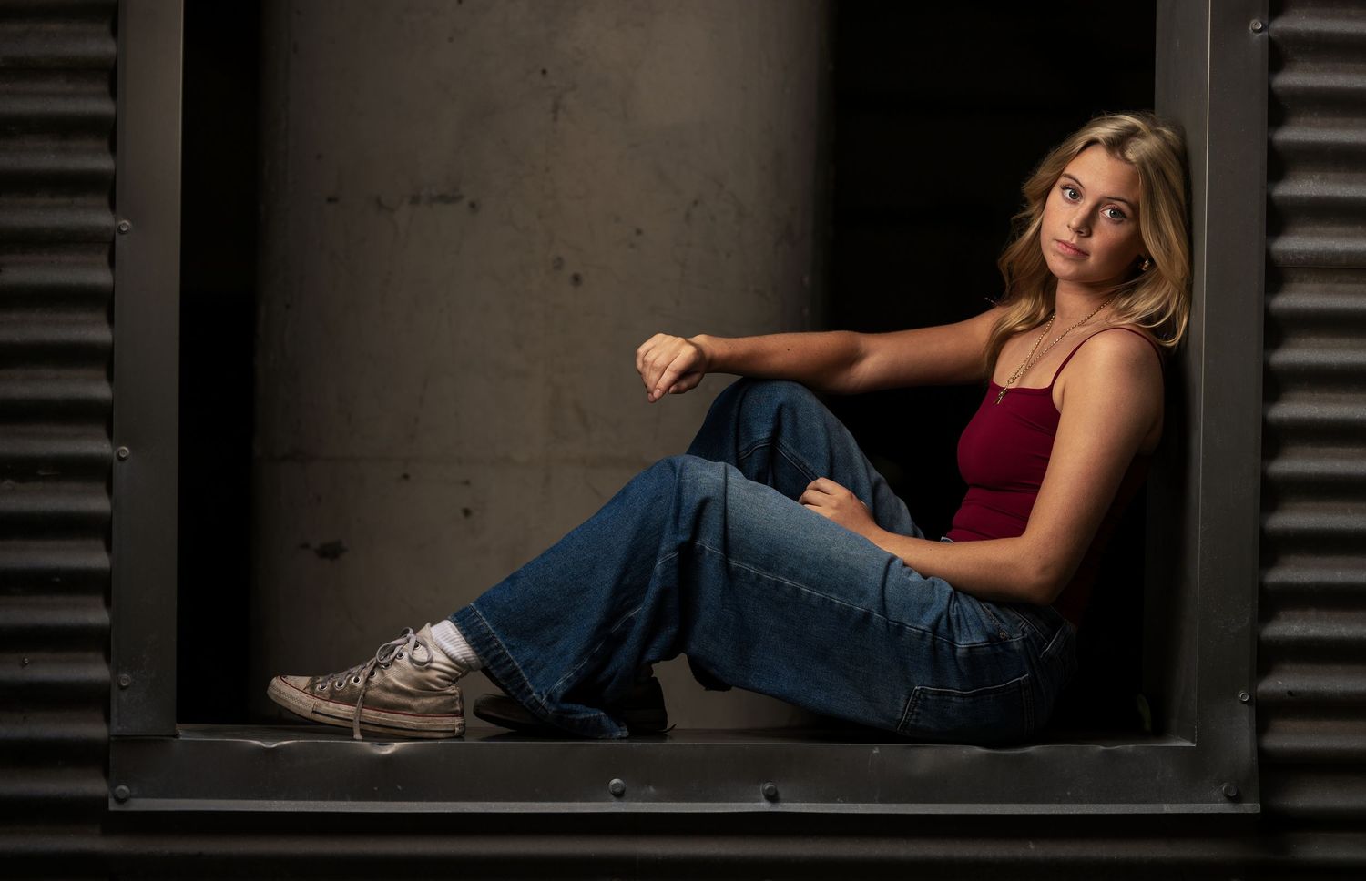 Senior portrait of a blonde girl in jeans photographed in an urban architectural setting