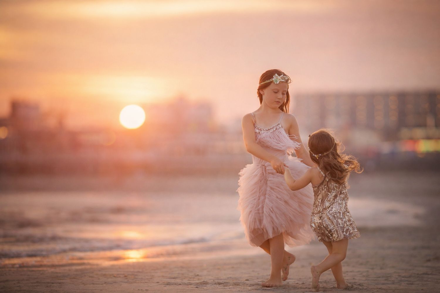 Two sisters dancing together on the beach at sunset during a portrait session in Wildwood, New Jersey.