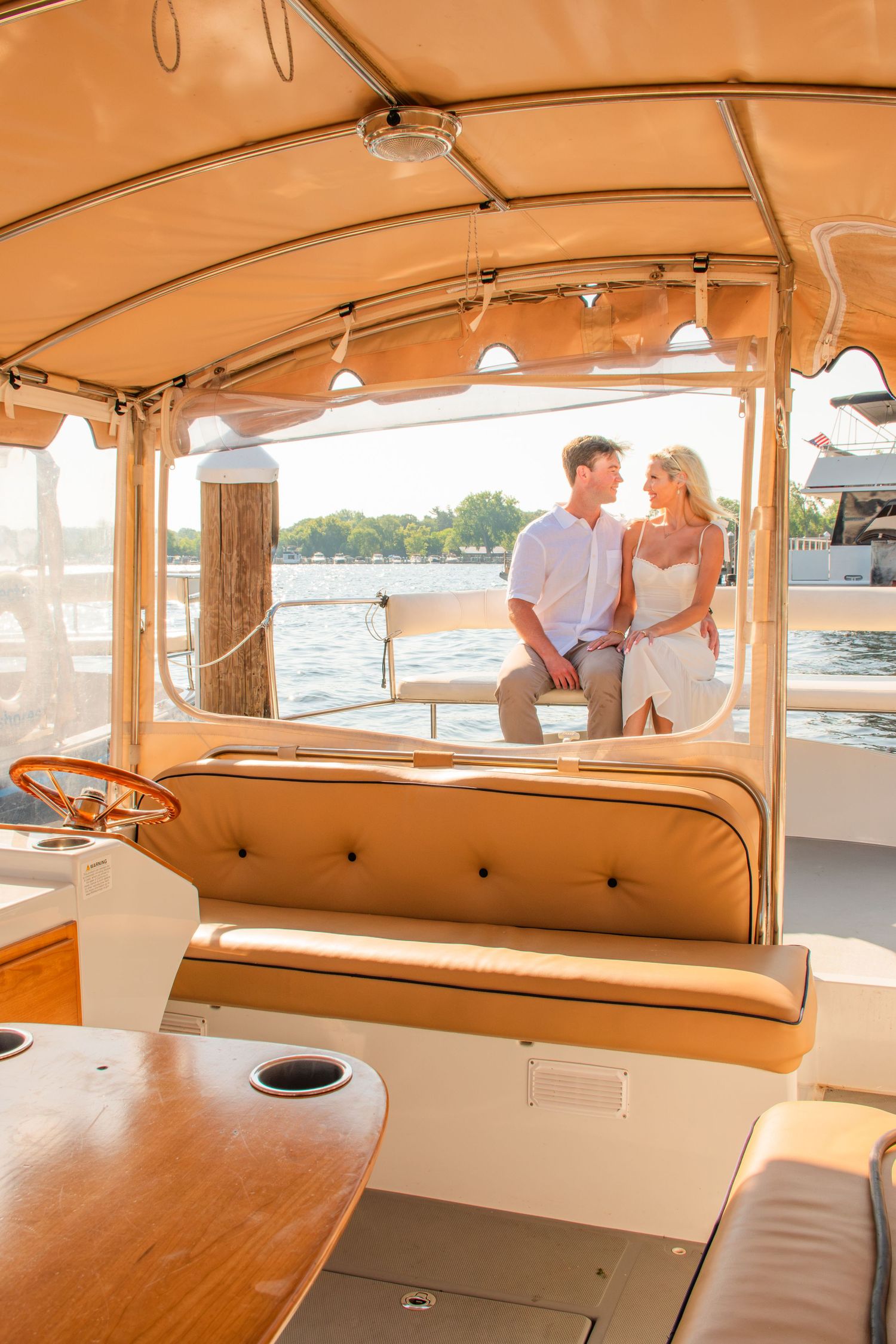 Couple sharing a romantic moment on a luxury wooden boat with tufted leather seating and water views.
