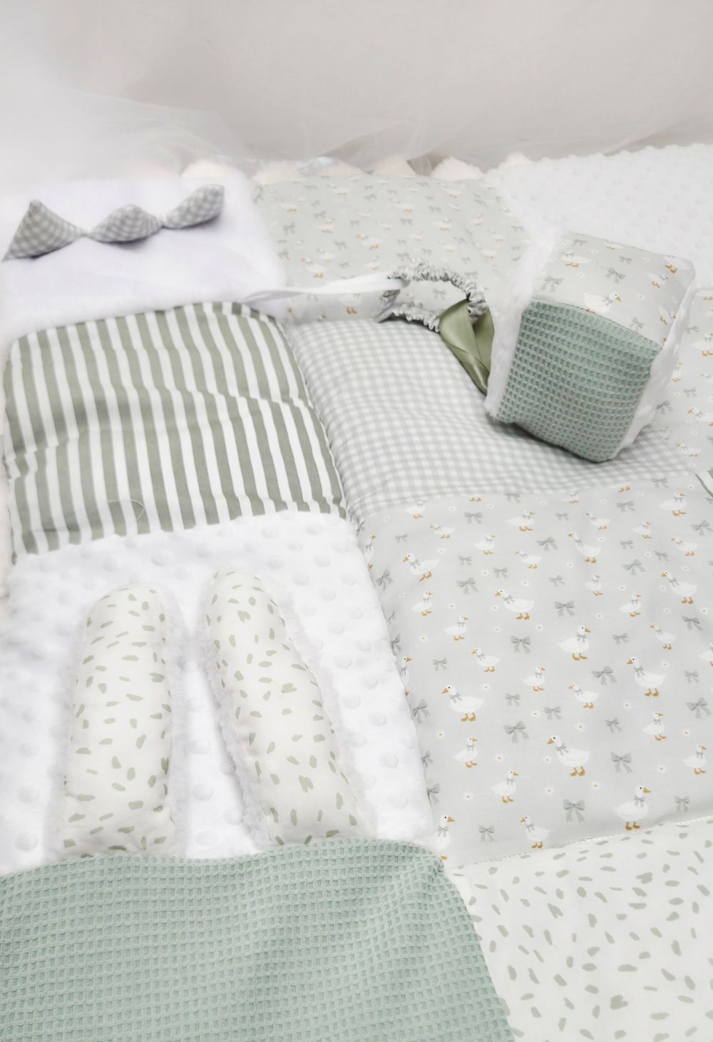 Sage green and white patchwork baby quilt set with striped, gingham, and floral fabric patches, coordinating pillows and accessories.