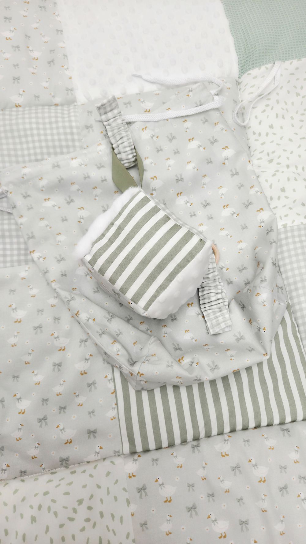 Soft sage green and white patchwork baby quilt with striped and floral fabric patterns, perfect for nursery decor.