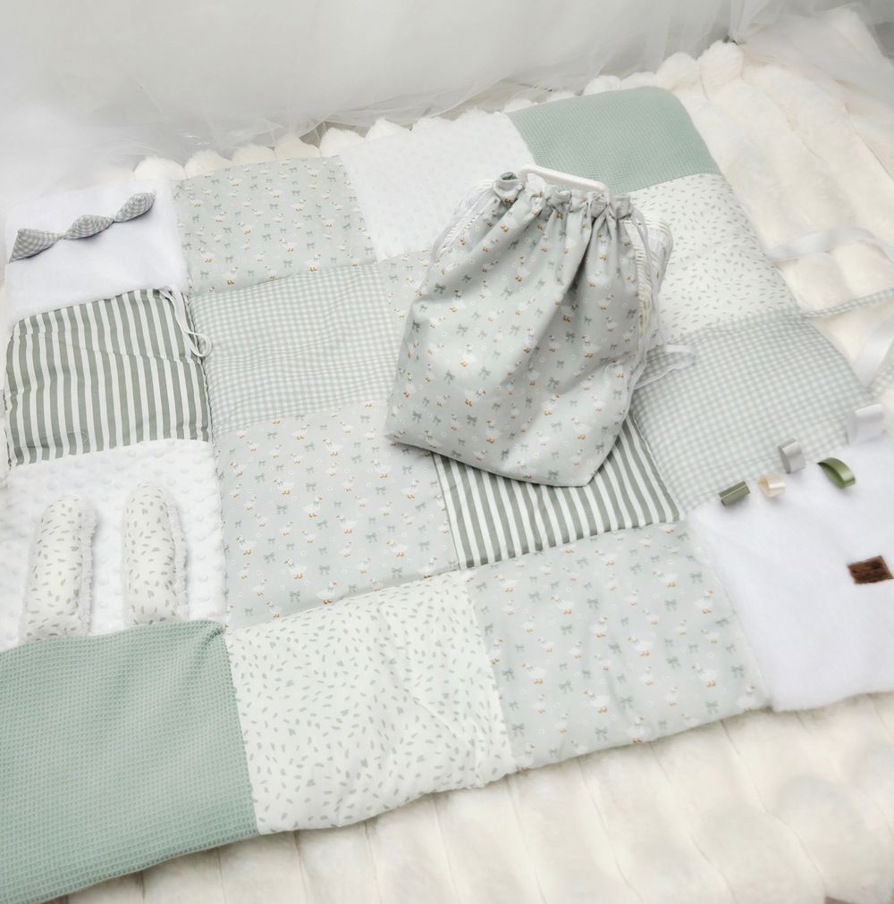 Sage green and white patchwork baby play mat with matching drawstring bag, featuring stripes and dot patterns.