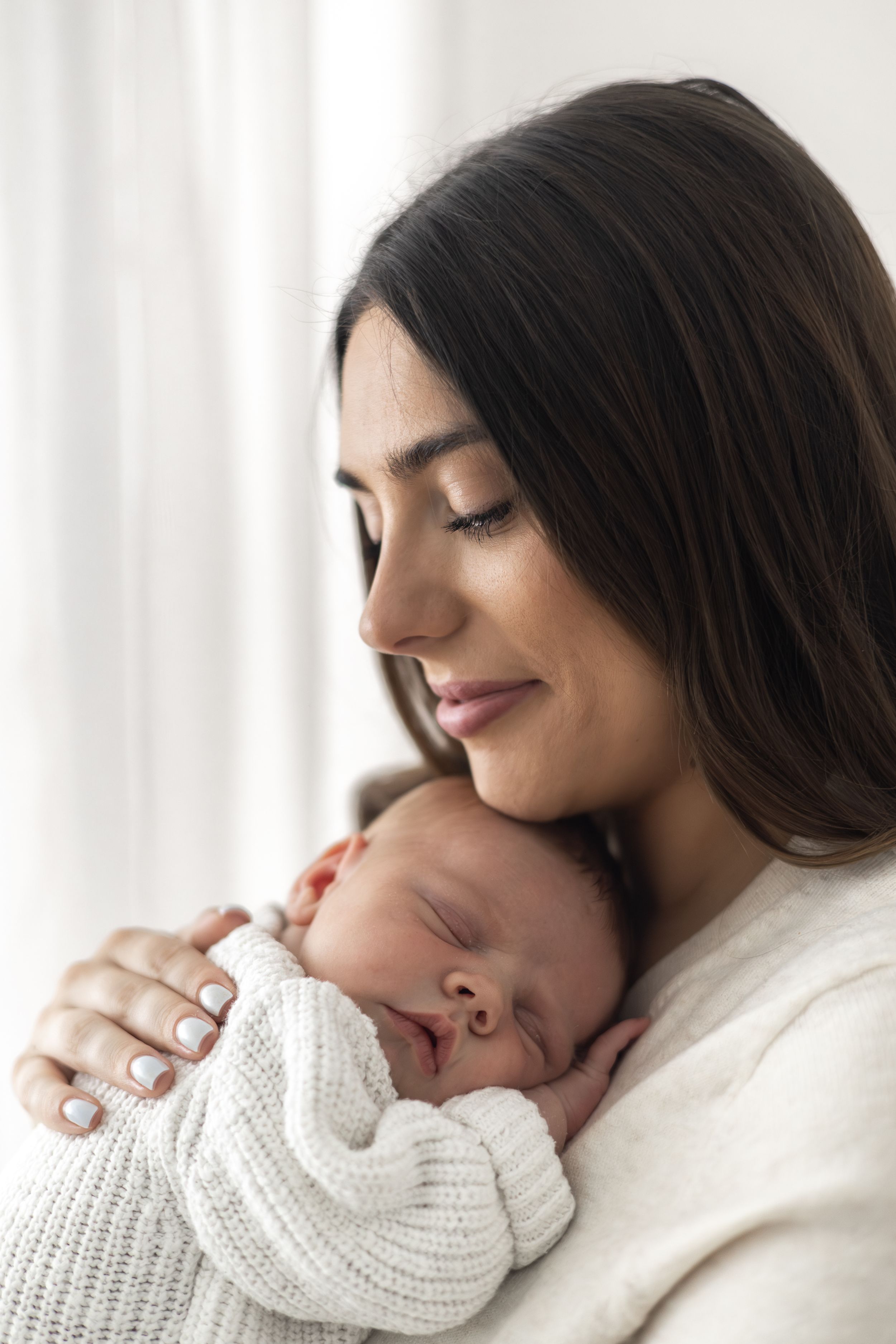 Mother cuddling her newborn baby during a relaxed newborn photography session