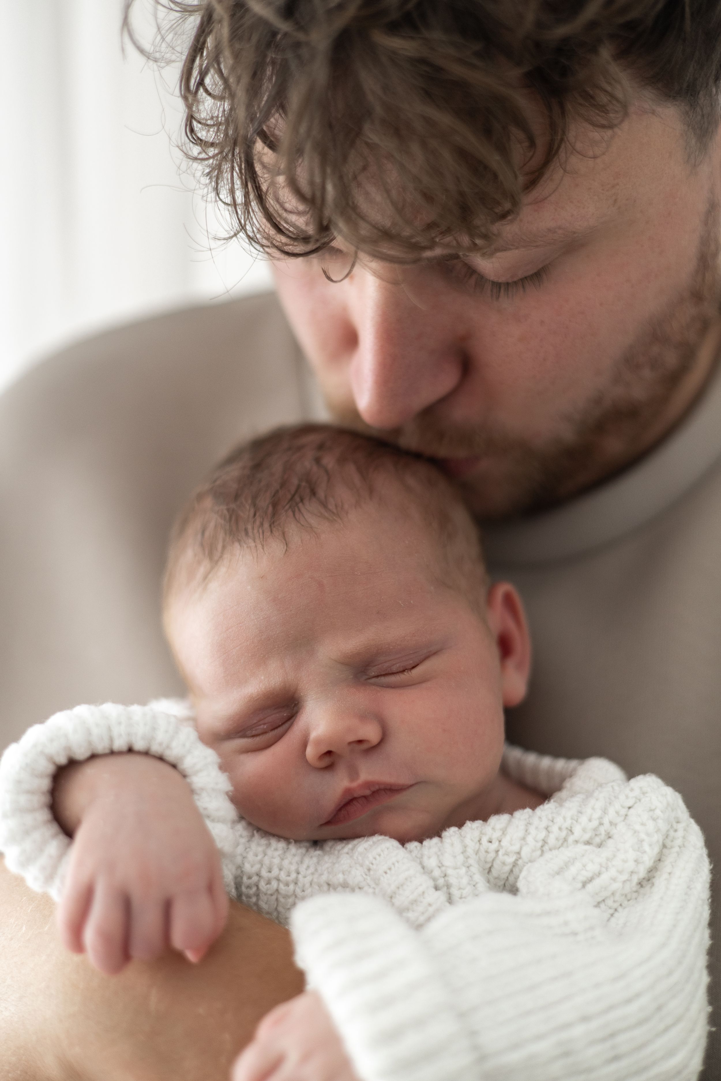Newborn baby being cuddled by dad during a relaxed photography session