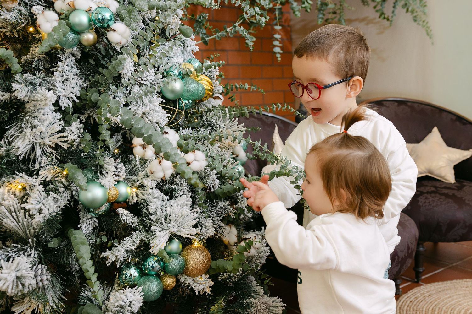 Family wearing coordinating burgundy outfits posed together near decorated Christmas tree.