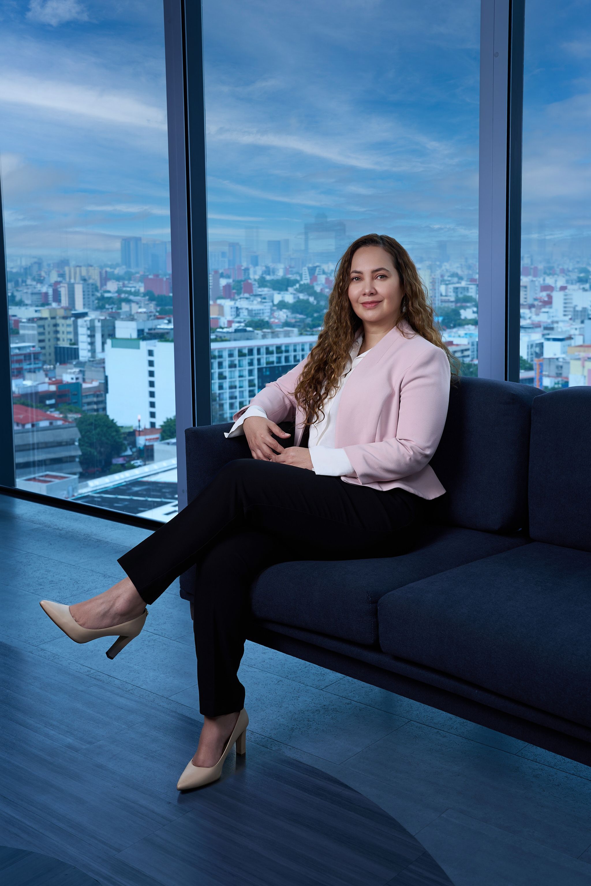 Retrato de directiva sentada en oficina con vista a Ciudad de México