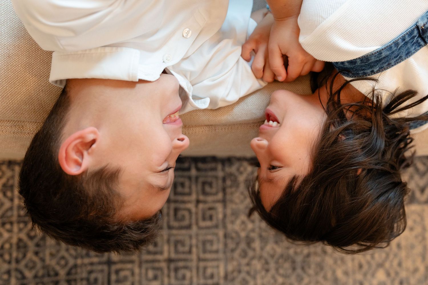 Overhead view of a happy couple lying on a couch, smiling and looking at each other tenderly.