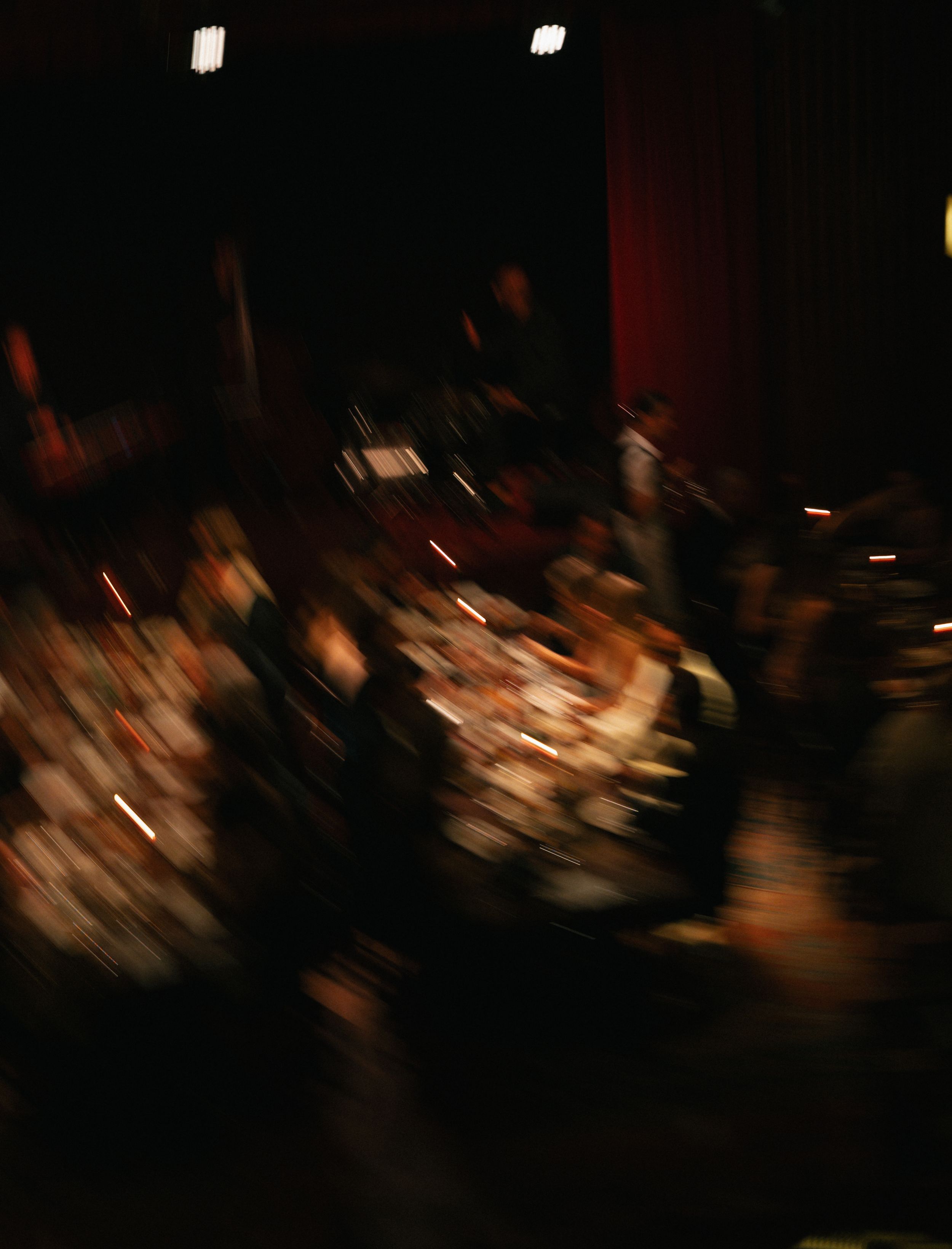 Blurry motion shot of an orchestra performing on a dimly lit stage during a live concert.