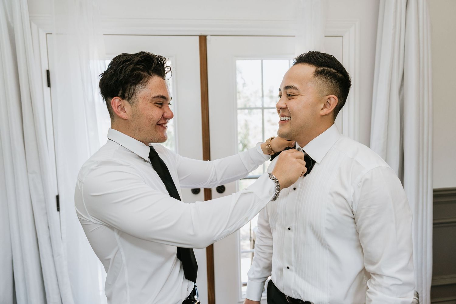 Groomsman helping Paul adjust his bow tie