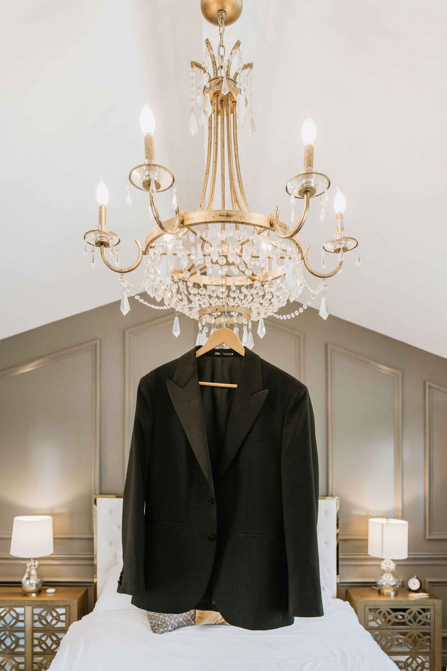 Paul’s black wedding tuxedo hanging beneath a chandelier
