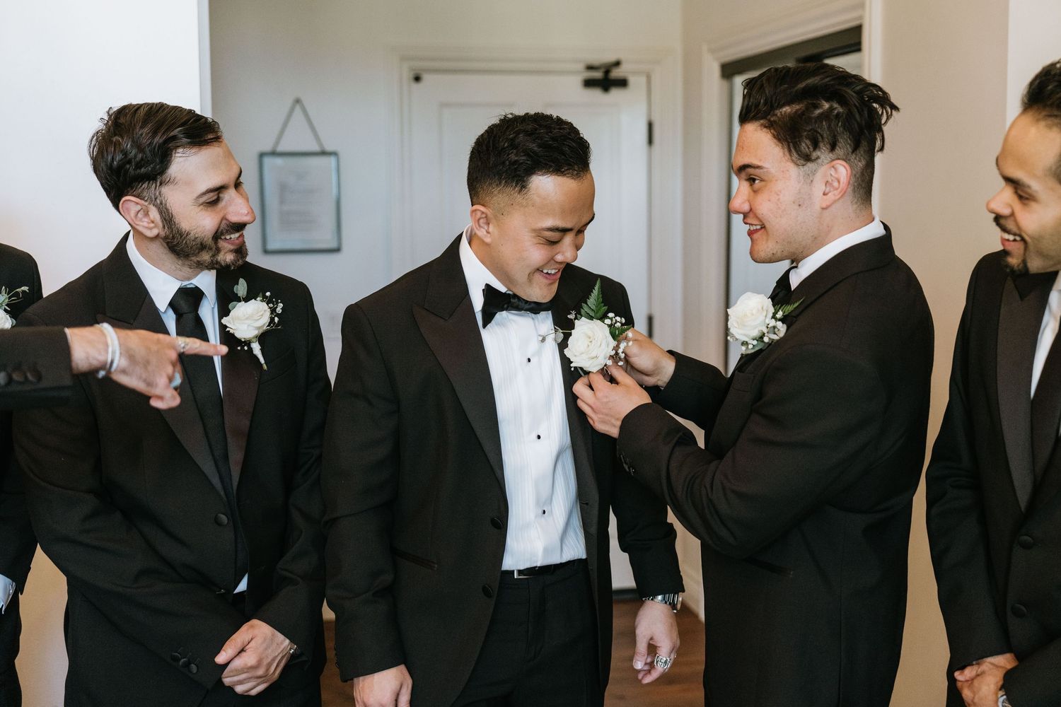 Groomsmen helping Paul attach his wedding boutonniere
