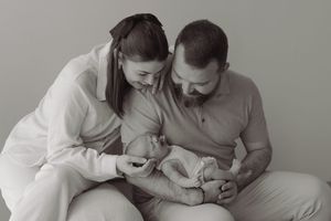 Black and white portrait of loving parents tenderly holding their sleeping newborn baby together.