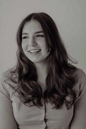 Black and white portrait of a young woman with long wavy hair smiling warmly at the camera.