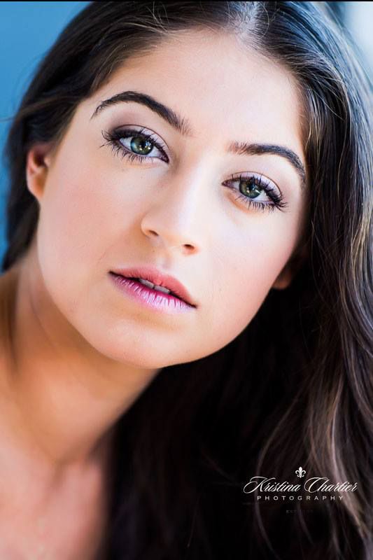 Close-up beauty portrait against blue background with soft lighting.