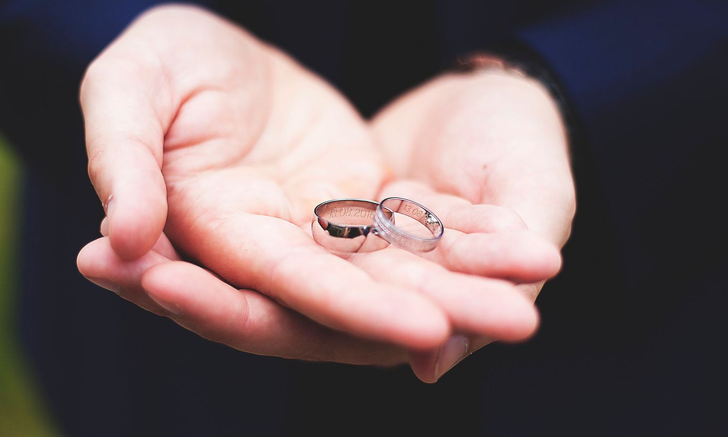 Two silver wedding rings resting in open palms, symbolizing love and commitment in a romantic ceremony.